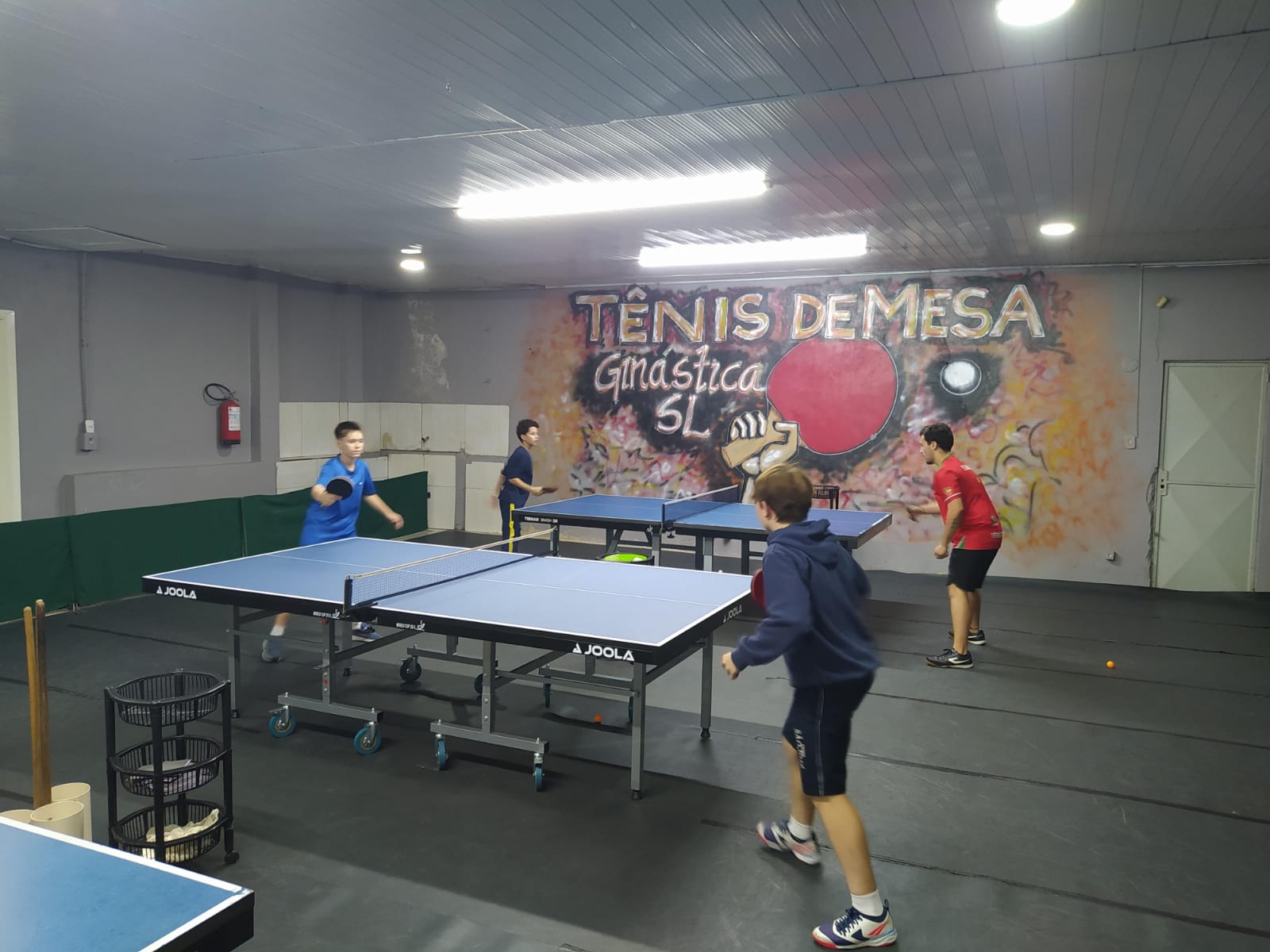Alunos praticando tênis de mesa em uma das mesas
